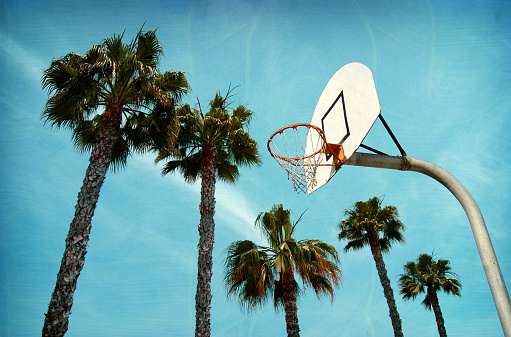aged and worn outdoor basketball hoop and palm trees