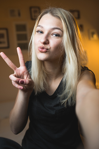 Hermosa chica adolescente alegre tomando un Selfie en dormitorio photo