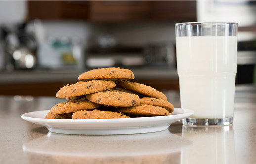 Delicious chocolate chip cookies in glass jars on wooden table in kitchen