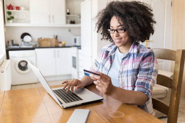 istock African woman sitting at home and using credit card 894696624