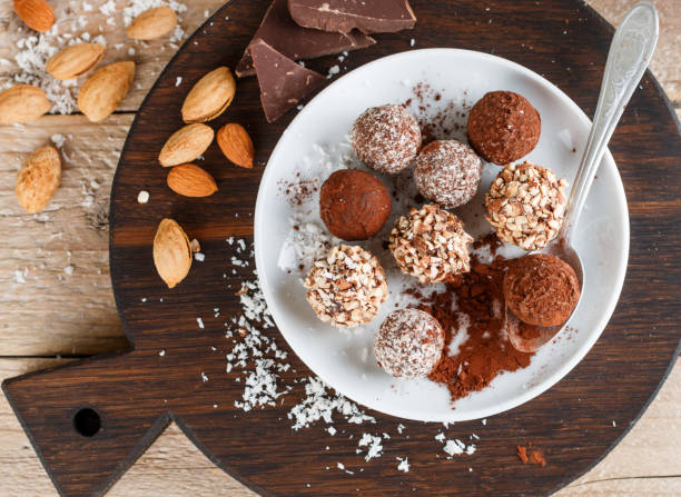 istock Prepare assorted dark chocolate truffles with cocoa powder, coconut and chopped almonds closeup. Homemade candy. Selective focus 894696906