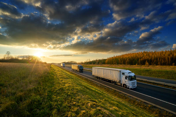 istock Three trucks driving on a highway in autumn landscape at sunset with dramatic clouds 894703590