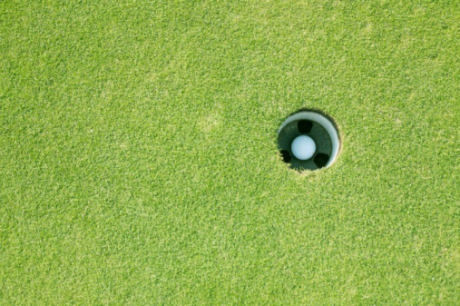 Drone perspective view of a golfer lining up a putt on the green. Shot on location on a golf course on the island of Moen in Denmark. Horizontal format with some copy space.