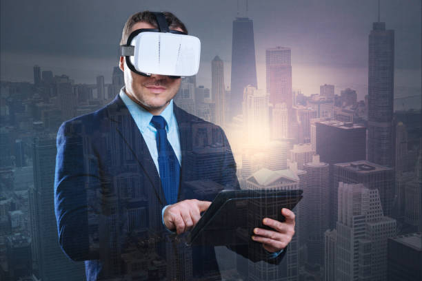 istock Handsome young businessman with touchpad trying on VR headset 894727854