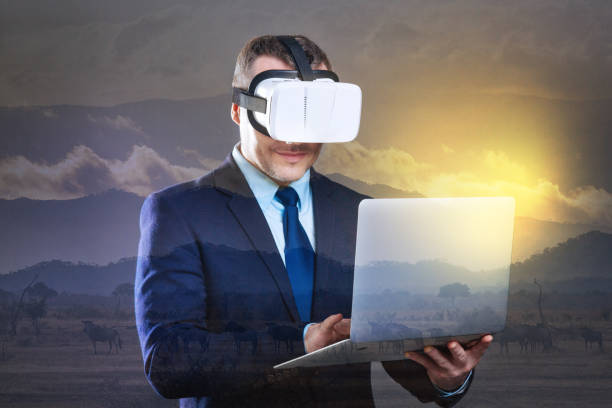 istock Joyful businessman working on laptop while wearing VR headset 894730552