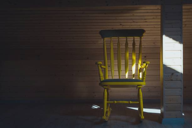 istock Sunlight Falling On Empty Yellow Rocking Chair By Wooden Wall 894741238
