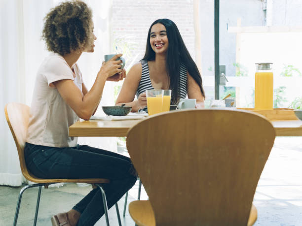 istock Happy lesbian couple talking and eating breakfast at dining table 894741592