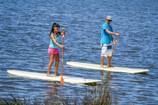 istock Man and woman stand up paddleboarding 894757778