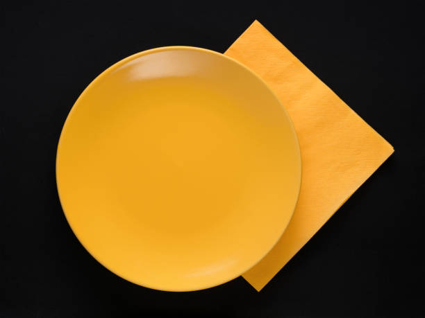 istock Yellow empty plate and napkin on black 894760156