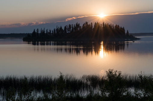 A calm and peaceful sunset evening at Astotin Lake, featuring the landmark Raspberry Island as the backdrop.