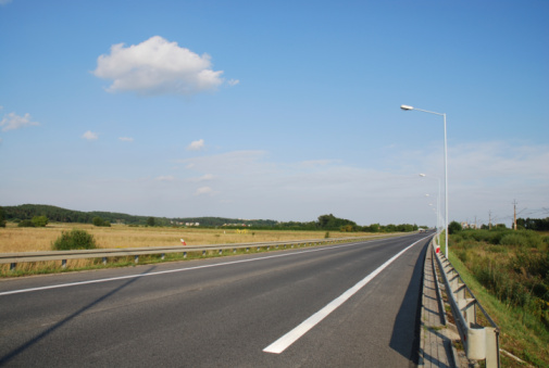 New asphalt lane of a highway divided by a many roadwork marks signs.