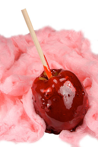 red candy apple circondato da zucchero filato di cotone rosa isolato - school carnival food cotton candy foto e immagini stock