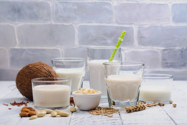 Assortment of non dairy vegan milk and ingredients Assortment of non dairy vegan milk and ingredients on white wooden background. Healthy drinks concept. Copy space coconut milk photos stock pictures, royalty-free photos & images