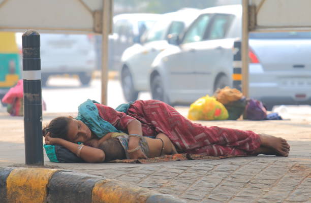 Homeless mother New Delhi India New Delhi India - October 27, 2017: Unidentified woman cuddle a baby and sleep on the street in downtown New Delhi India india poverty stock pictures, royalty-free photos & images