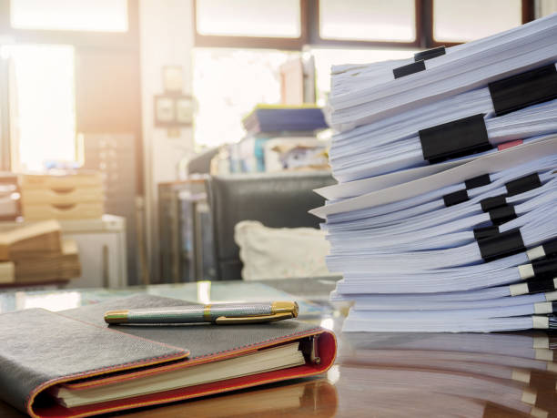 istock Close up of a pen and business documents stack on desk in office at morning 894835834
