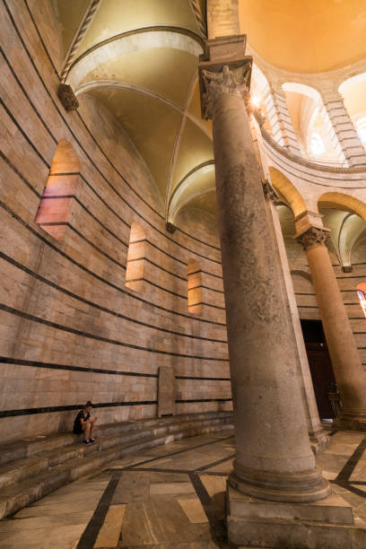 teen mädchen sitzt auf den steinernen stufen in das riesige baptisterium auf dem feld der wunder, pisa, italien - pisa tuscany italy baptistery stock-fotos und bilder