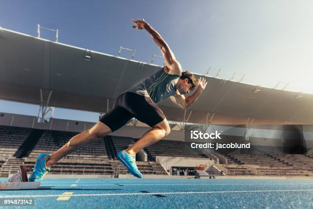 Sprinter Despegar Del Bloque Que Comienza En La Pista De Atletismo Foto de stock y más banco de imágenes de Deporte