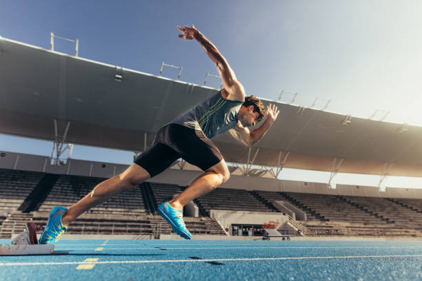 Sprinter taking off from starting block on running track Runner using starting block to start his run on running track in a stadium. Athlete starting his sprint on an all-weather running track. track and field stock pictures, royalty-free photos & images