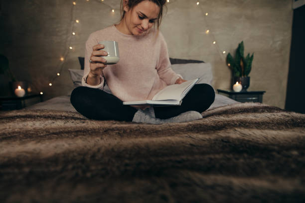 istock Relaxed woman on bed reading book with coffee 894875856