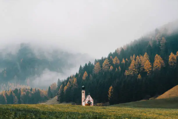 Scenic view of St. Johann church in  Dolomites mountains in fog , Italy