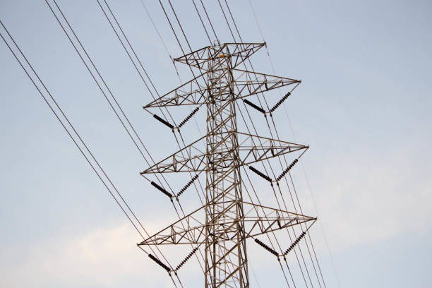 istock Electrical grid transmission power lines with wind turbines and sunset, and blue sky. high voltage pole in countryside 894922184