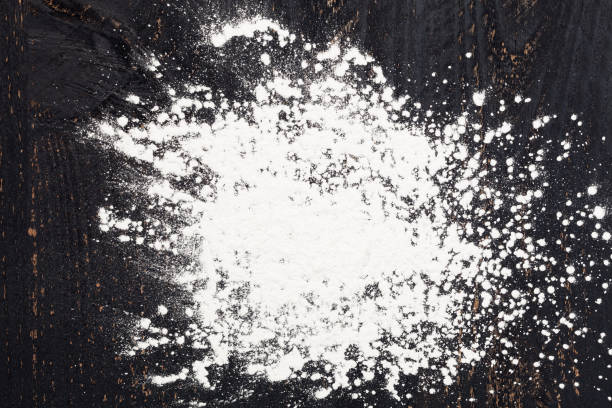 istock sprinkle wheat flour with copy space for text on dark black wood background, top view for cooking dough or pastry background. 894922456