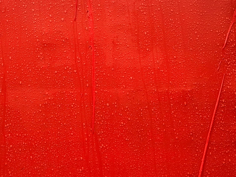 Texture water rain drops on the red plastic surface close up as a background