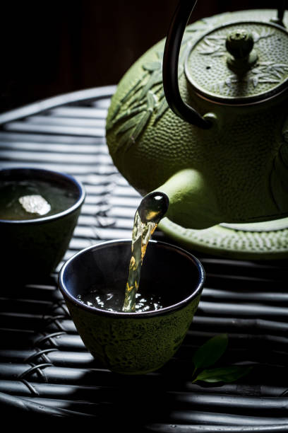 istock Pouring green tea into tea cup from with teapot 894943396