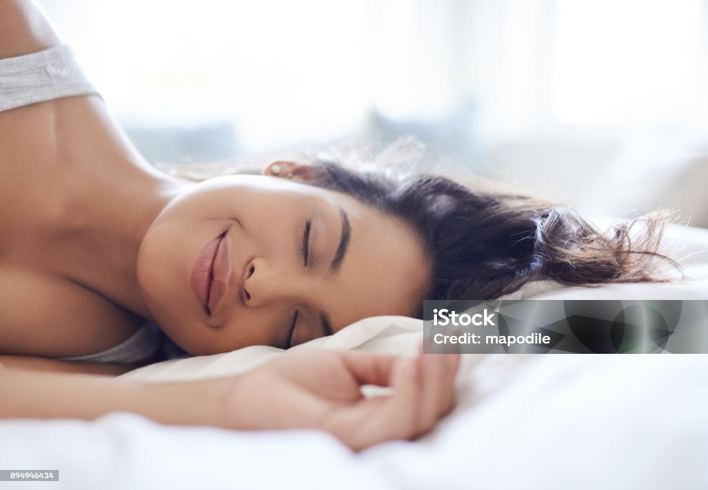 Relax, you're on weekend time now Shot of an attractive young woman relaxing on her bed in the morning at home Sleeping Stock Photo