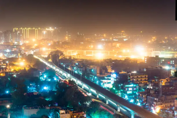 aerial view of the cityscape of Noida gurgoan delhi at night  with the elevated metro track and metro station visible. The city residences and offices are also clearly visible