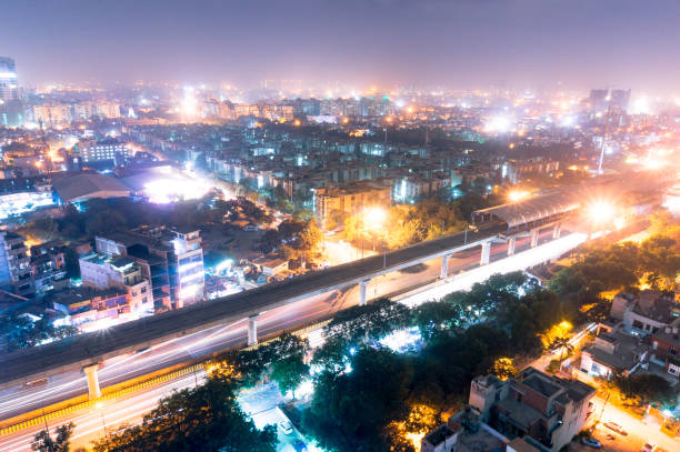 Noida metro station at night against the cityscape aerial view of the cityscape of Noida gurgoan delhi at night  with the elevated metro track and metro station visible. The city residences and offices are also clearly visible hyderabad india stock pictures, royalty-free photos & images