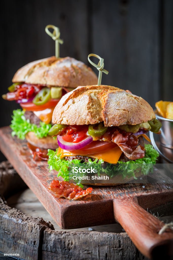 Hamburger mit Speck, Tomaten und Rindfleisch auf Holzbrett gemacht - Lizenzfrei Brotsorte Stock-Foto