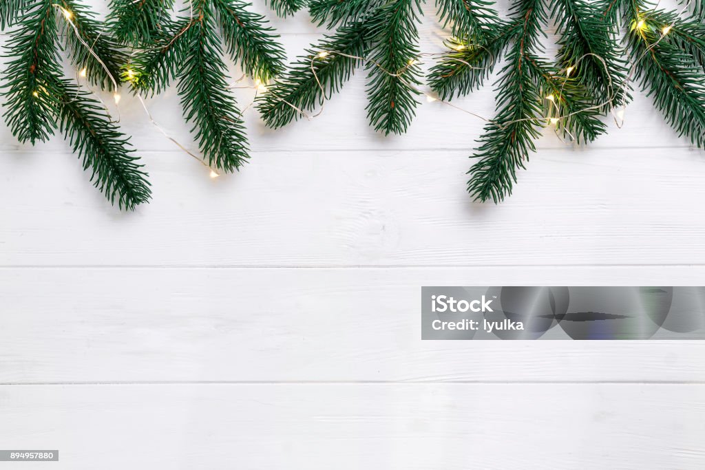 christmas or new year background Christmas composition. Christmas fir branches with lights on wooden white background. Flat lay, top view copy space Christmas Lights Stock Photo