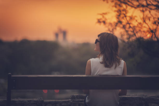 istock Woman sitting on a bench and watching the distant city scenery. 894966054
