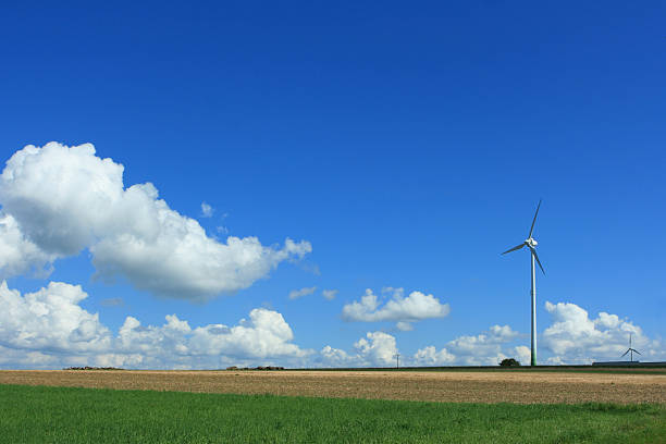 Wind turbine is standing in the beautiful summer landscape with green pasture and blue sky. This picture is taken in Luxembourg.