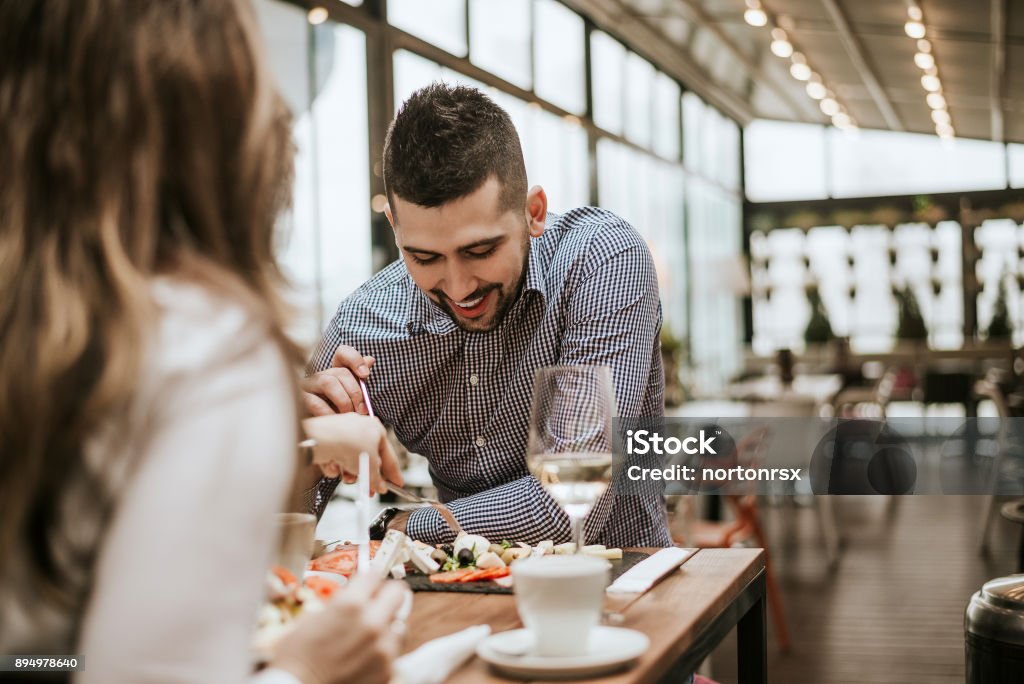 Hombre guapo en el restaurante con un amigo comiendo. - Foto de stock de Restaurante libre de derechos