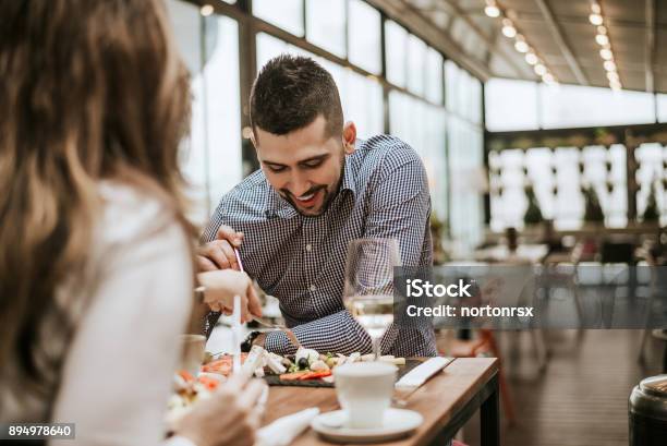 Photo libre de droit de Bel Homme Au Restaurant Avec Un Ami Manger banque d'images et plus d'images libres de droit de Restaurant - Restaurant, Tous types de couple, Prendre son repas