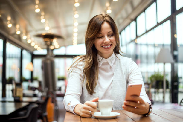 istock Young brunette woman at cafe drinking coffee and using mobile phone 894980808