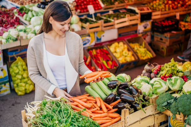 View at young woman buying vegetables at the market. View at young woman buying vegetables at the market. farmers market healthy lifestyle choice people stock pictures, royalty-free photos & images