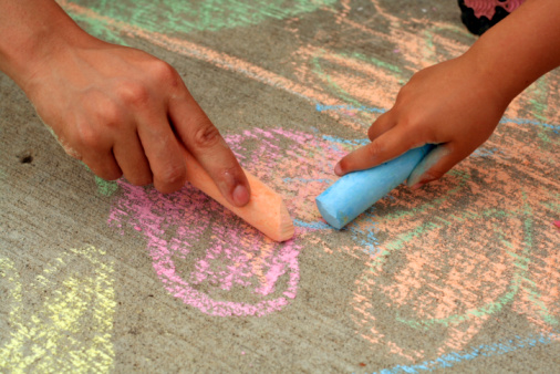 Little child drawing happy family with chalk on asphalt