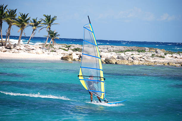 A man windsurfing near the coast on a sunny day Windsurfing in Mayan Riviera, Mexico.   windsurfing stock pictures, royalty-free photos & images