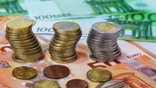 istock Stacked one and two Euro coins with paper banknotes. 894994704