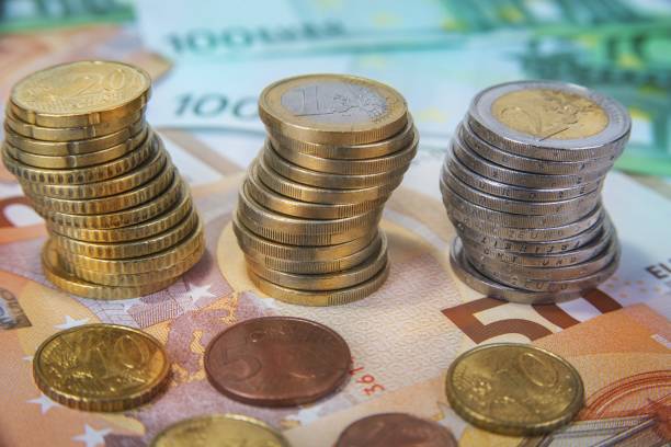 istock Stacked one and two Euro coins with paper banknotes. 894997204