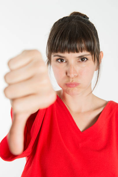 istock A young woman making a thumb down with a frumpy facial expression 895010504