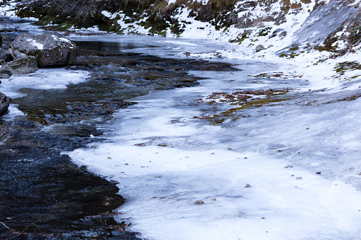 frozen river in the Ordesa natural park, with big stones and transparent waters