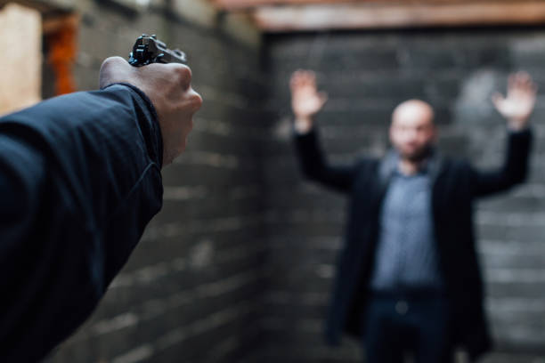 istock A man holding gun pointed to another man with his hands raised 895041998