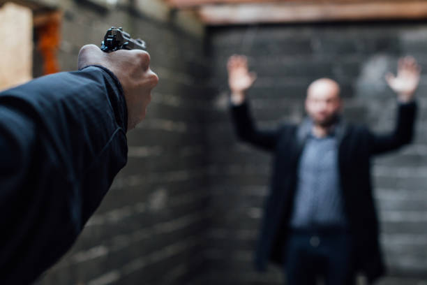 um homem segurando a arma apontada para outro homem com as mãos levantadas - gun handgun violence kidnapping - fotografias e filmes do acervo