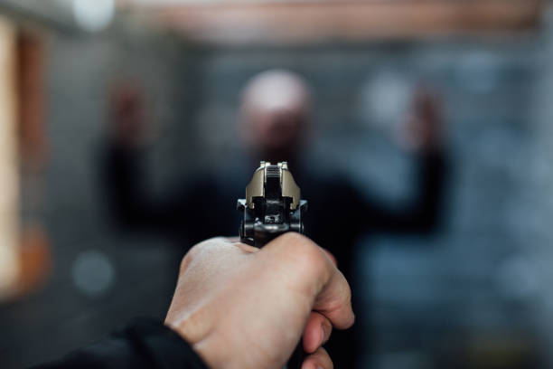 istock A man's hand holding a gun pointed to another man 895042018