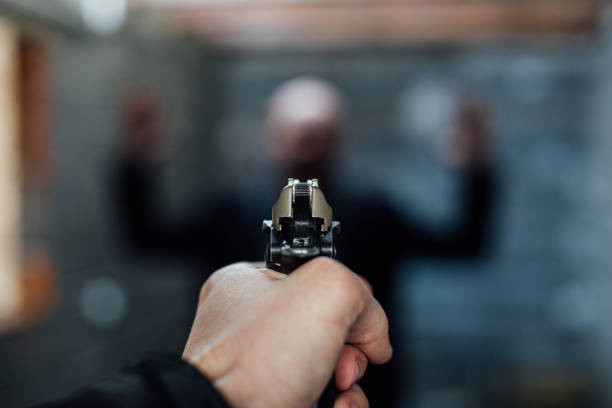 a man's hand holding a gun pointed to another man - gun handgun violence kidnapping imagens e fotografias de stock