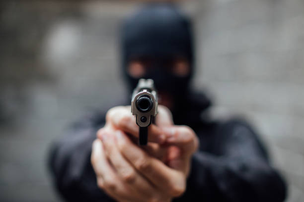 un homme couvert de visage braqué un fusil sur la lentille - gun handgun violence kidnapping photos et images de collection